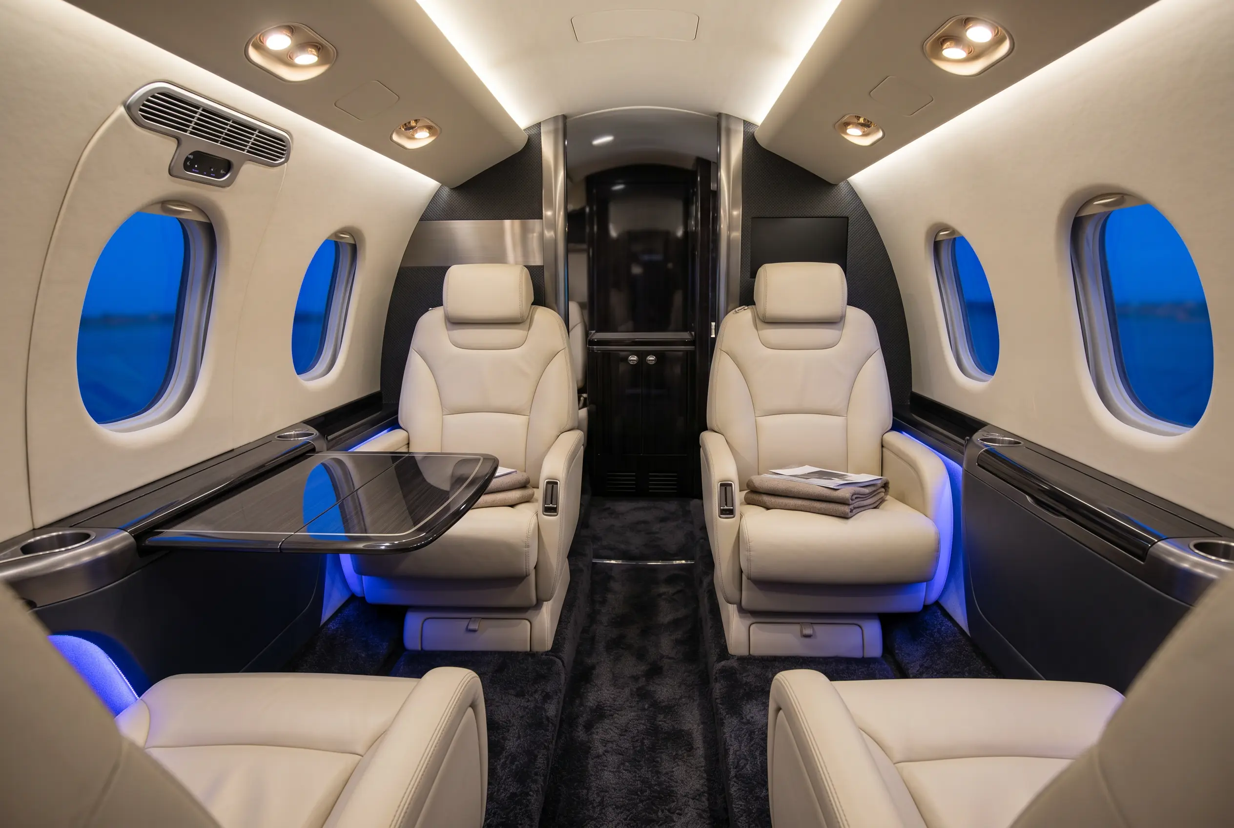Bright light jet cabin in club-four configuration with cream leather seats — typical interior for a New York to Miami light jet charter