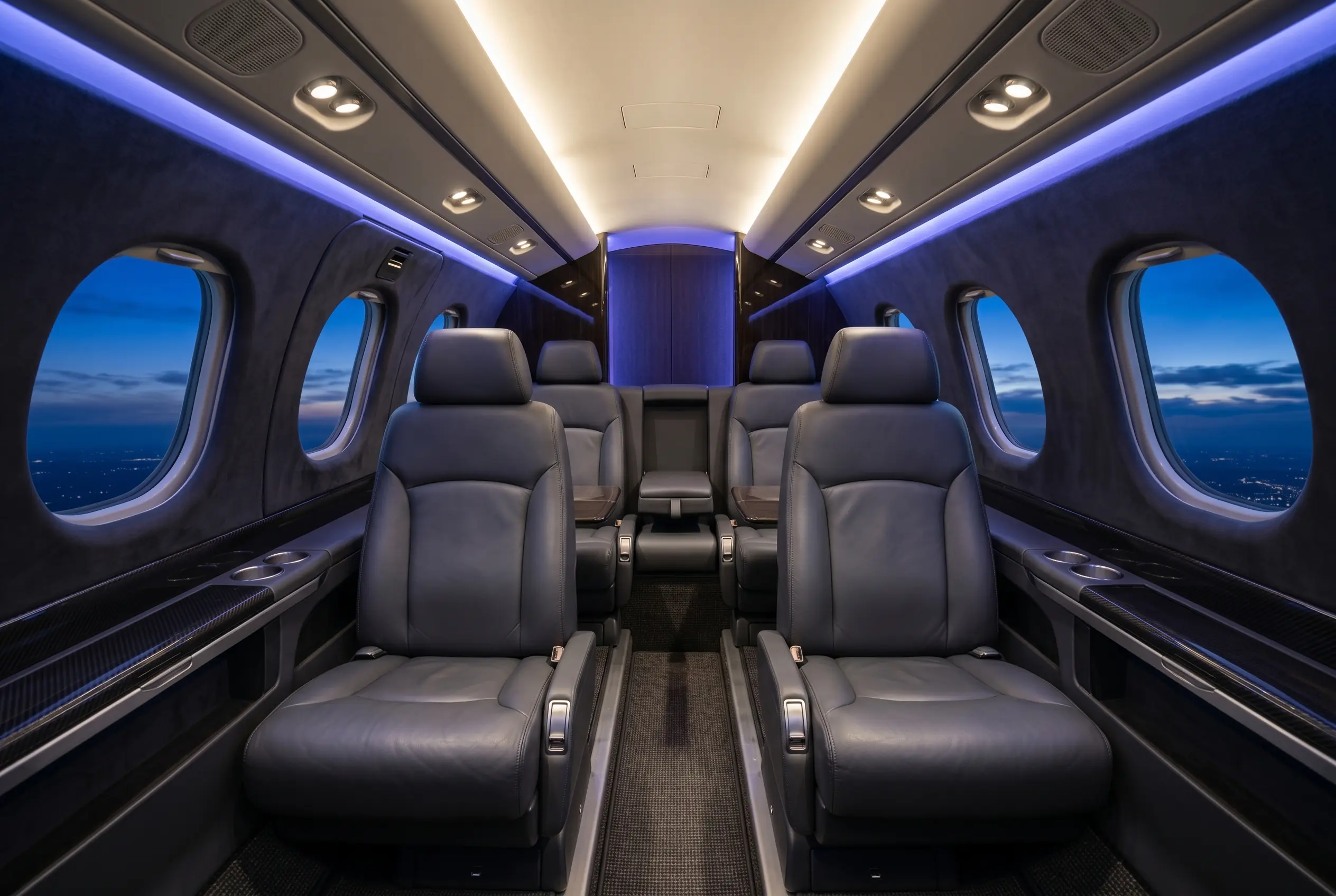 Embraer Phenom 100EV cabin with four club seats and large oval windows, configured for a New York to Miami charter