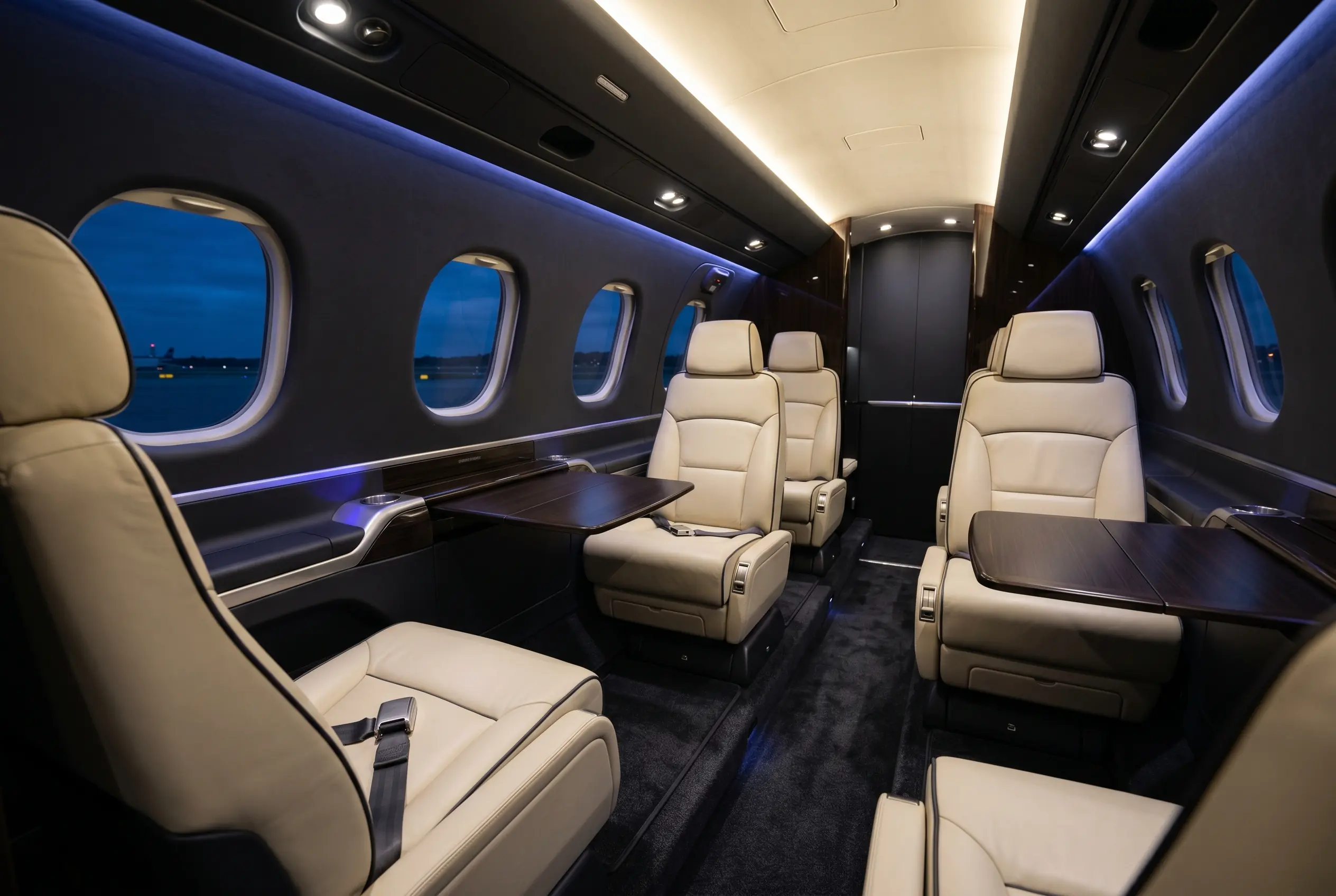 Embraer Phenom 300E cabin with cream leather club seating and large oval windows, ready for a New York to Miami charter